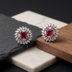 Pair of silver earrings with red gemstones on a dark surface