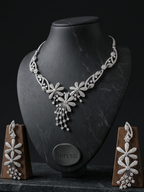 Silver necklace and earrings set on a black mannequin bust with 'Soreva' branding.