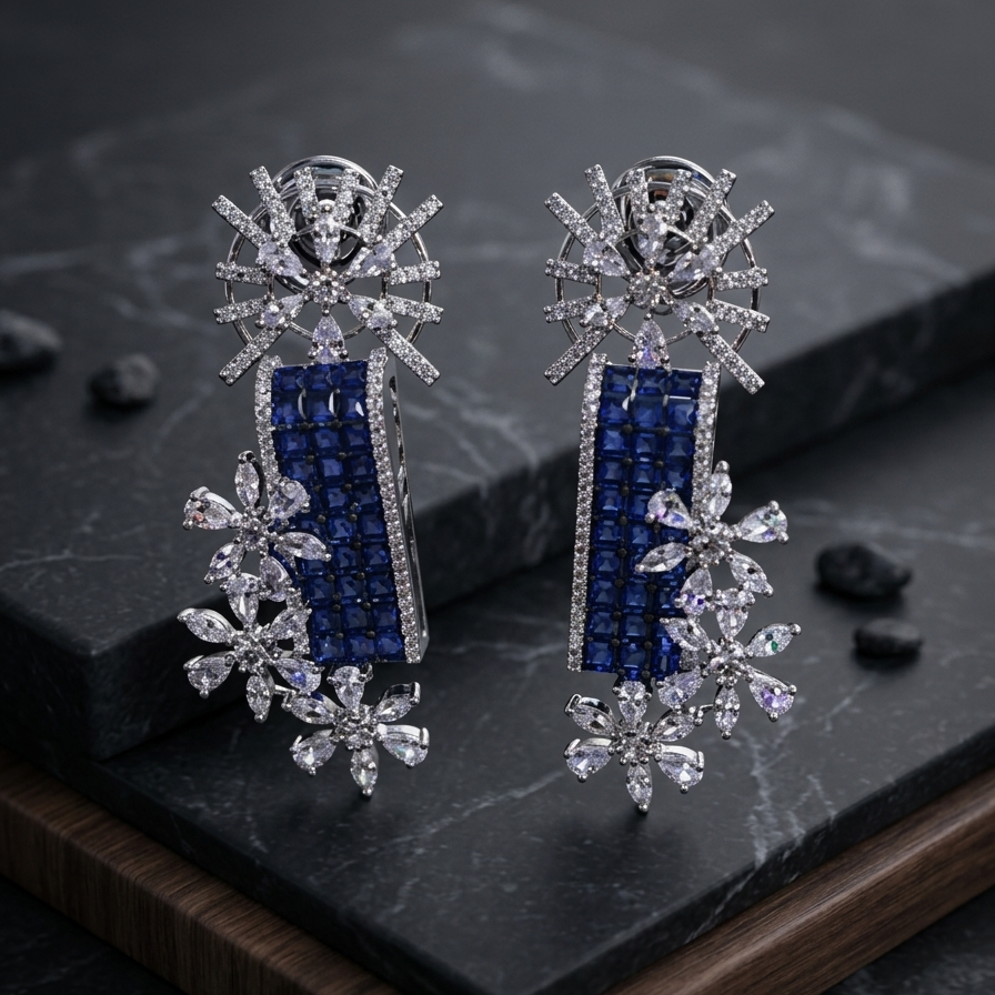 Pair of silver earrings with blue and clear gemstones on a dark surface