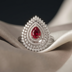 Teardrop-shaped ring with a red gemstone on a white fabric background
