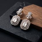 Pair of diamond earrings on a dark surface with a wooden block background