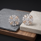 Pair of silver and gold earrings on a stone surface with a dark background