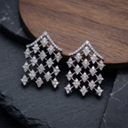 Diamond earrings on a dark stone surface with a wooden background