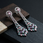 Pair of elegant earrings with pink and green gemstones on a dark surface