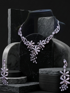 Delicate silver necklace and earrings on a dark stone surface