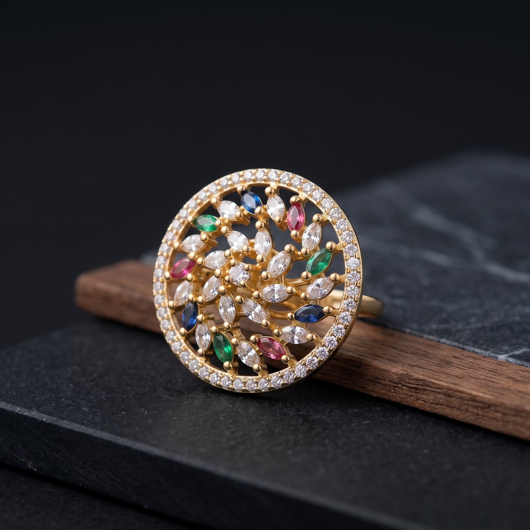 Gold ring with colorful gemstones on a dark surface