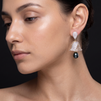 Close-up of a woman wearing a dangling earring with a black gemstone on a dark background