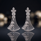 Pair of diamond earrings on a reflective surface with a blurred background
