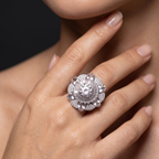 Close-up of a hand wearing a sparkling diamond ring on a neutral background