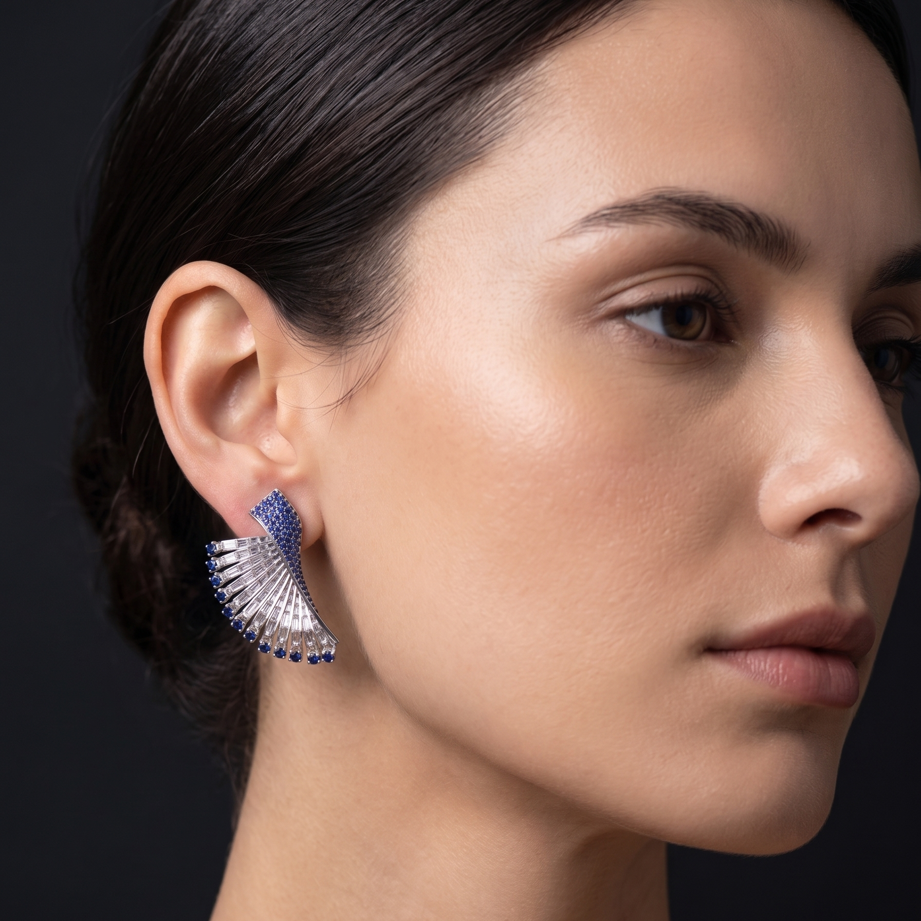 Close-up of a woman wearing a blue earring against a dark background