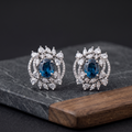 Pair of silver earrings with blue gemstones on a dark surface