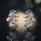 Pair of silver earrings with pearls on a reflective surface
