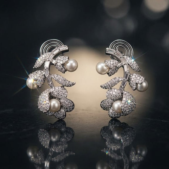 Pair of silver earrings with pearls on a reflective surface